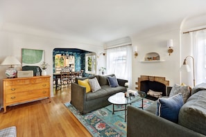 A living room with a fireplace, a dining area, and a kitchen visible through an archway. - Spacious 5-bedroom house with AC, hot tub and space to spread out (Seattle)