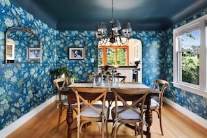 A dining room with a wooden table, chairs, and a blue floral wallpaper. - Spacious 5-bedroom house with AC, hot tub and space to spread out (Seattle)