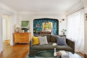 A living room with a sofa, a glass coffee table, and a dining area in the background. - Spacious 5-bedroom house with AC, hot tub and space to spread out (Seattle)