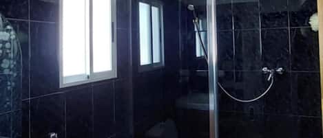 A bathroom with a toilet, a shower enclosure, and a sink.