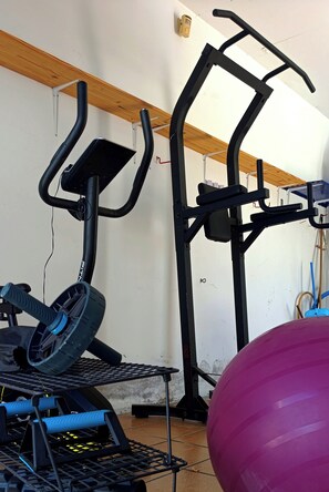 Academia com equipamentos de ginástica, incluindo uma máquina elíptica e uma bicicleta ergométrica.