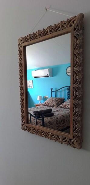 Quarto com cama, mesa de cabeceira com abajur e ar-condicionado fixado na parede.