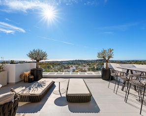A rooftop terrace with a clear view of the cityscape, furnished with a sofa, a small table, and potted plants. - Exceptional duplex penthouse with panoramic views in Aloha (Marbella)