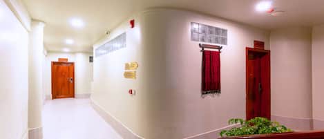 A hallway with a curved wall, a red door, and a plant.