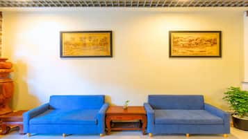 Una habitación con dos sofás azules, una mesa de centro de madera y dos obras de arte enmarcadas en la pared.