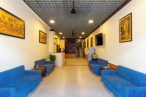 A hallway with blue sofas, a reception desk, and framed artwork on the walls. - Siemreap City Angkor Central (Krong Siem Reap)