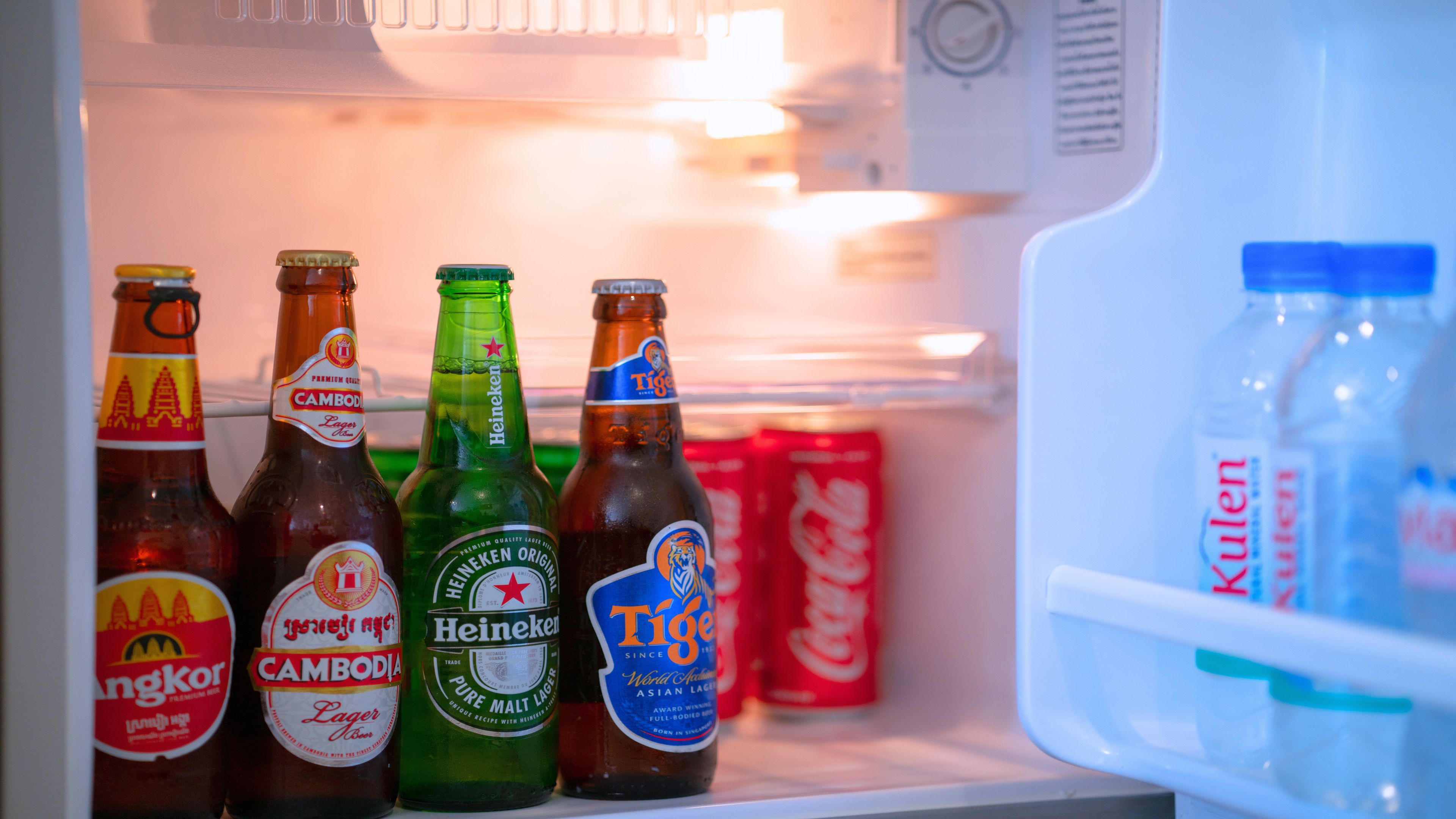Ein Kühlschrank mit verschiedenen Bierflaschen und einem Wasserspender.