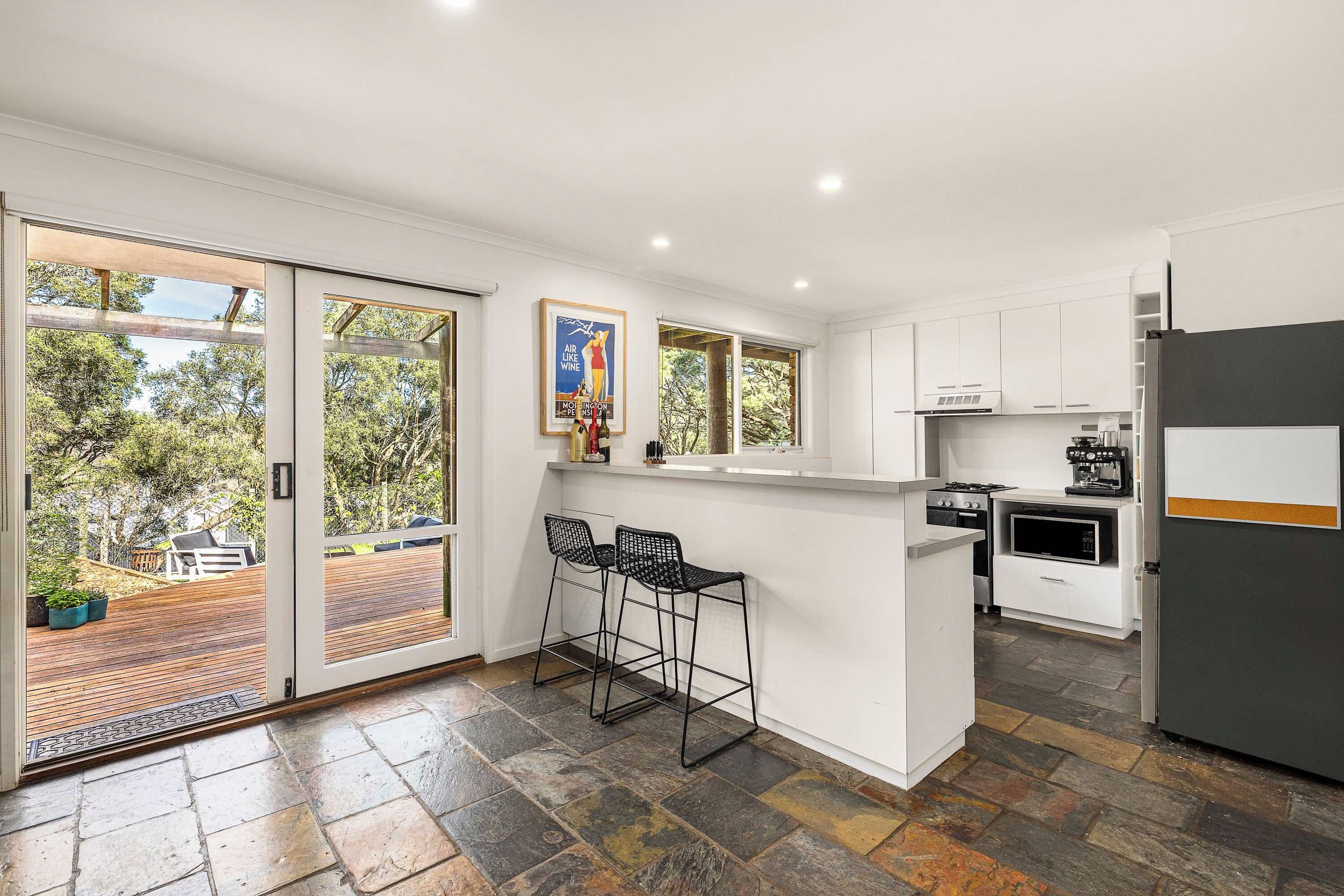 A modern kitchen with a bar area, large windows, and a view of the outdoors.