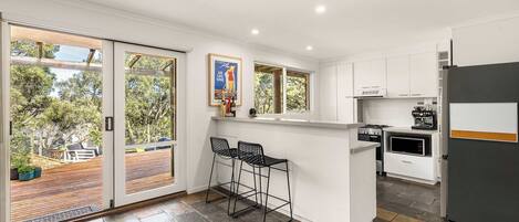 A modern kitchen with a bar area, large windows, and a view of the outdoors.