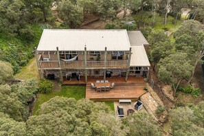 A two-story house with a deck, outdoor seating, and a small pond. - The Stillhouse | Sauna, Soak & Pet-Friendly Escape (Rye)