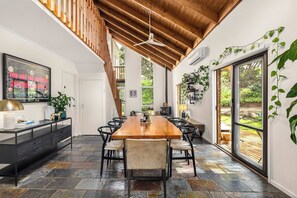 A spacious kitchen with a large wooden table, black chairs, and a stone tile floor. - The Stillhouse | Sauna, Soak & Pet-Friendly Escape (Rye)