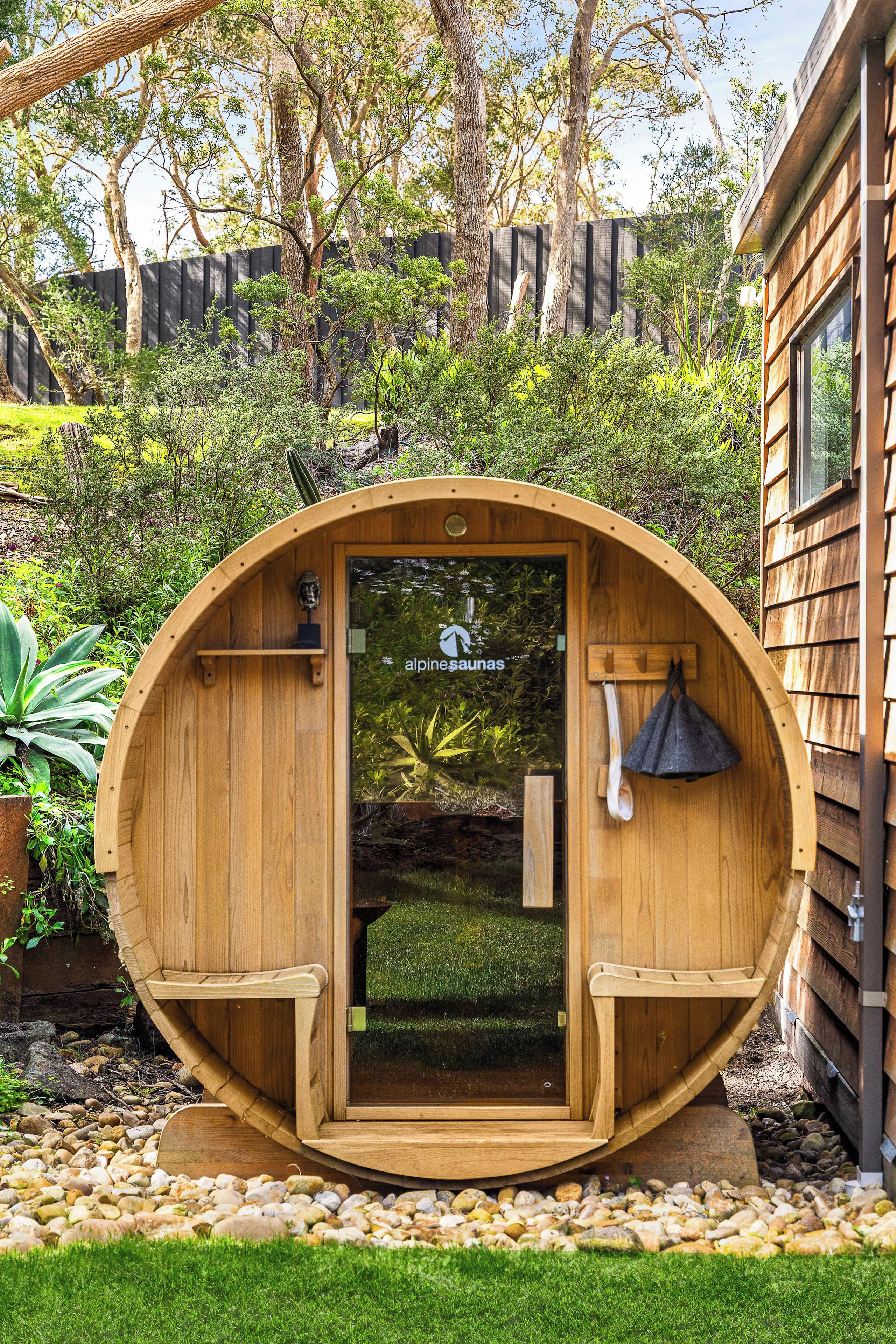 Une structure de sauna en bois, dotée d’une porte, d’une cloche et d’un logo.