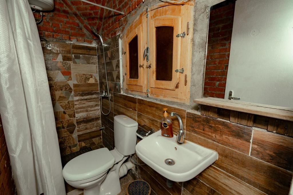 Een badkamer met toilet, wastafel en houten kastjes.