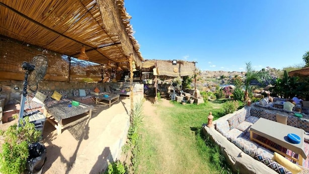 A courtyard with outdoor seating, a thatched-roof structure, and a view of the surrounding landscape. - Krouma Camp & Ecolodge (Aswan)