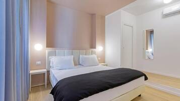 Een slaapkamer met een bed, nachtkastjes, een spiegel en een deur.