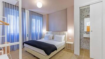 Een moderne hotelkamer met een bed, nachtkastjes, een bureau en een badkamer met spiegel en wastafel.