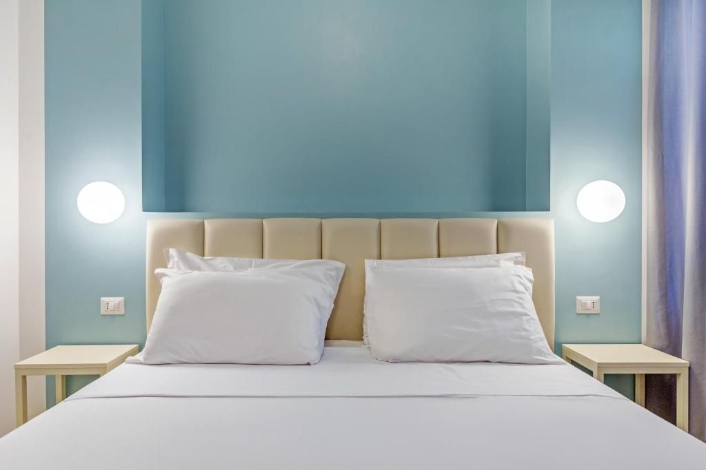Une chambre d’hôtel avec un lit, deux tables de chevet et une tête de lit.