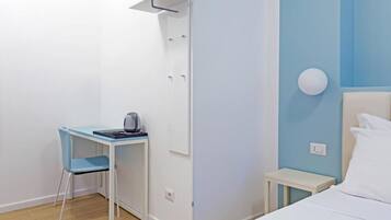 Une petite pièce, bien rangée, comprenant un lit, un bureau avec une chaise et une armoire.