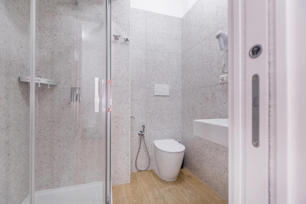 Une salle de bain moderne avec une douche à parois de verre, des toilettes blanches et un lavabo.