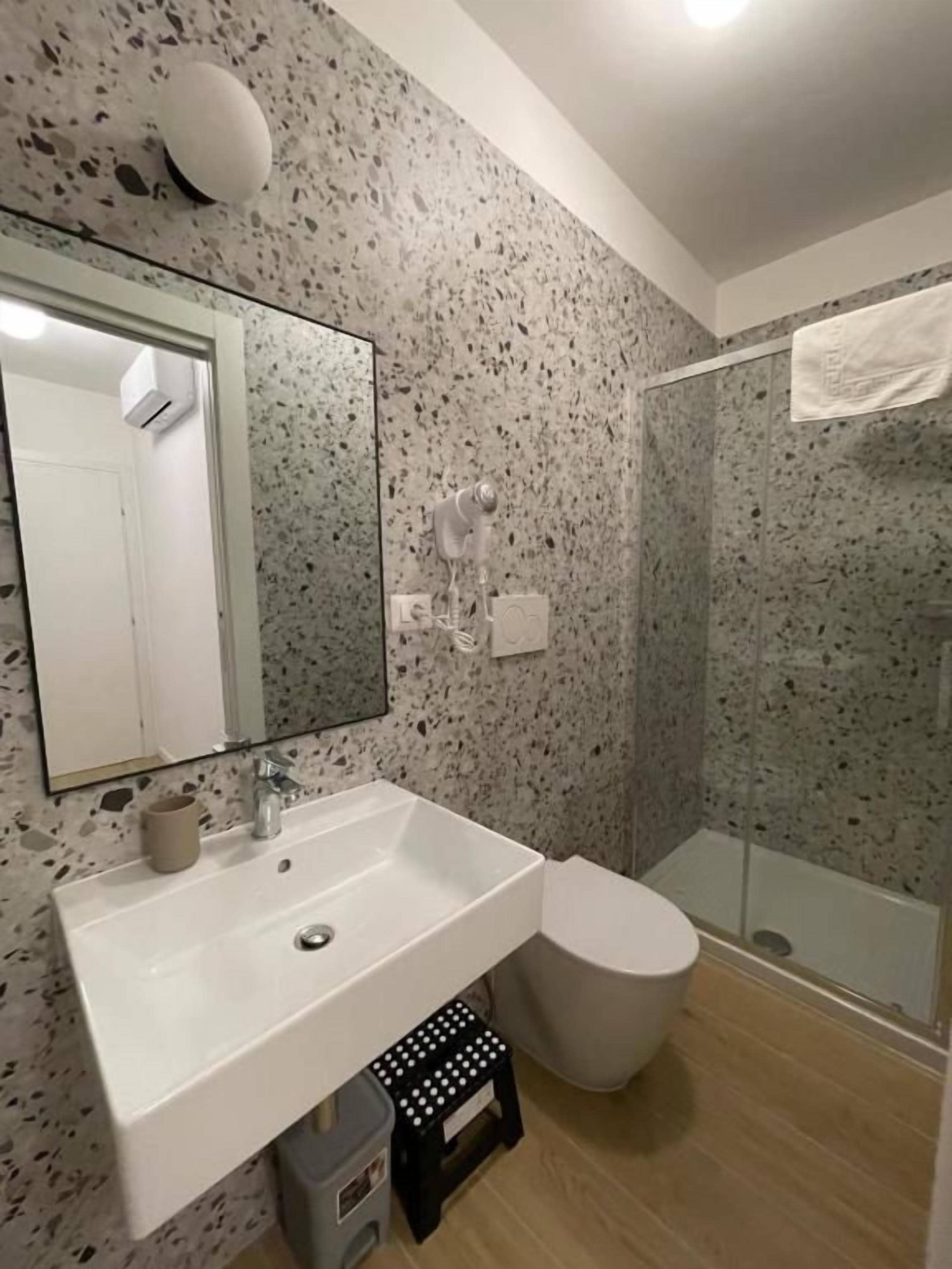 Une salle de bain avec un lavabo blanc, des toilettes et une douche à parois de verre.