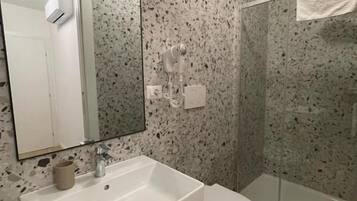 Une salle de bain avec un lavabo blanc, des toilettes et une douche à parois de verre.