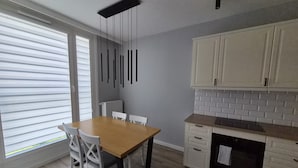 Eine moderne Küche mit weißen Schränken, einem Holztisch und einer Pendelleuchte.