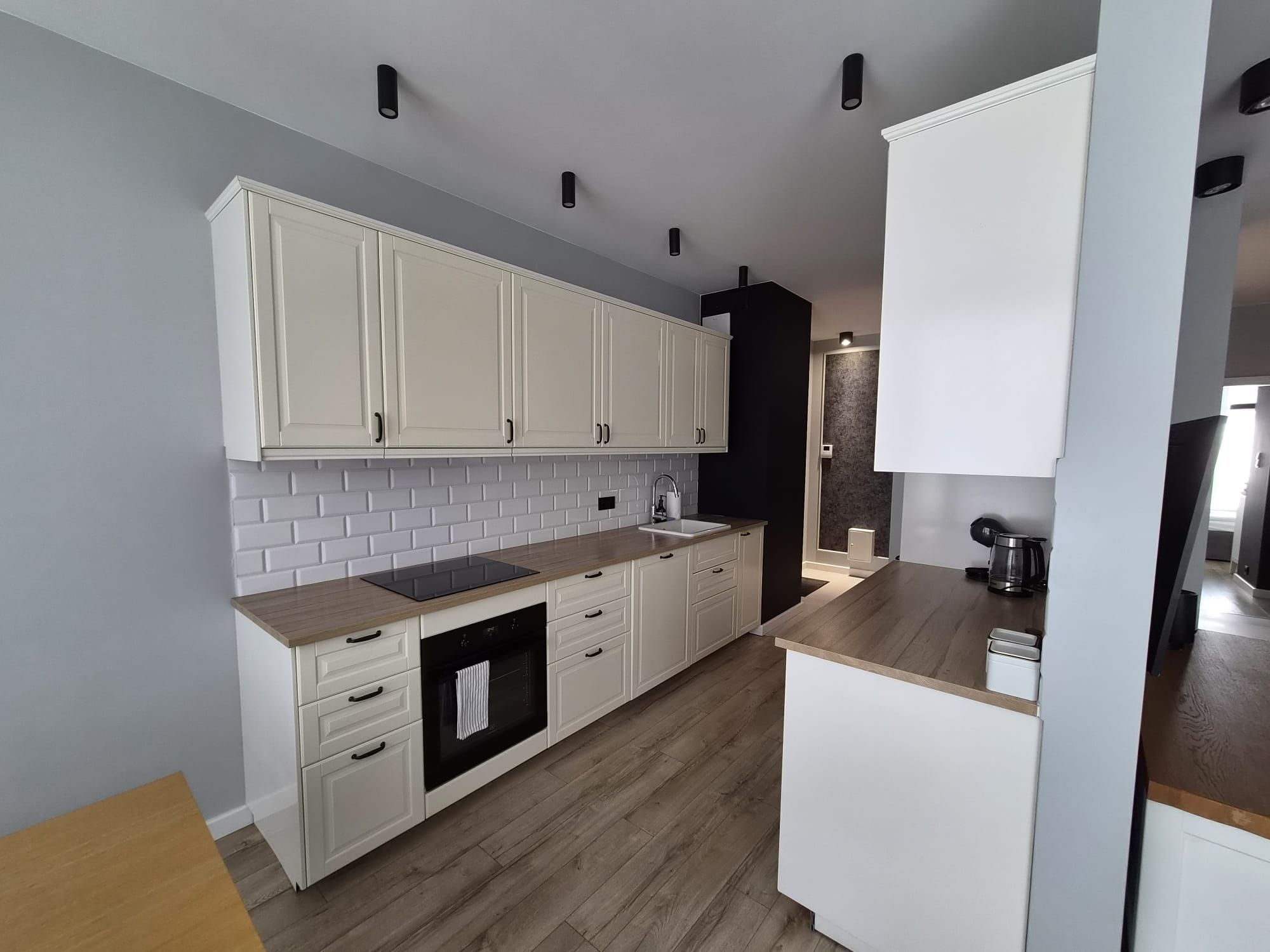 Eine moderne Küche mit weißen Schränken, einem schwarzen Backofen und einer Holzauskastung.