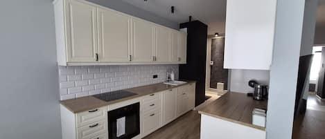 A modern kitchen with white cabinets, a black oven, and a wooden countertop.