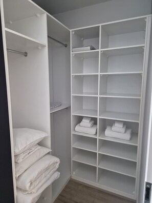 Ein begehbarer Kleiderschrank mit mehreren Regalen und Ablageflächen, aufgeräumt zur Aufbewahrung.