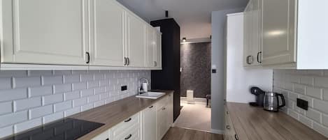 A modern kitchen with white cabinets, a black backsplash, and wooden countertops.