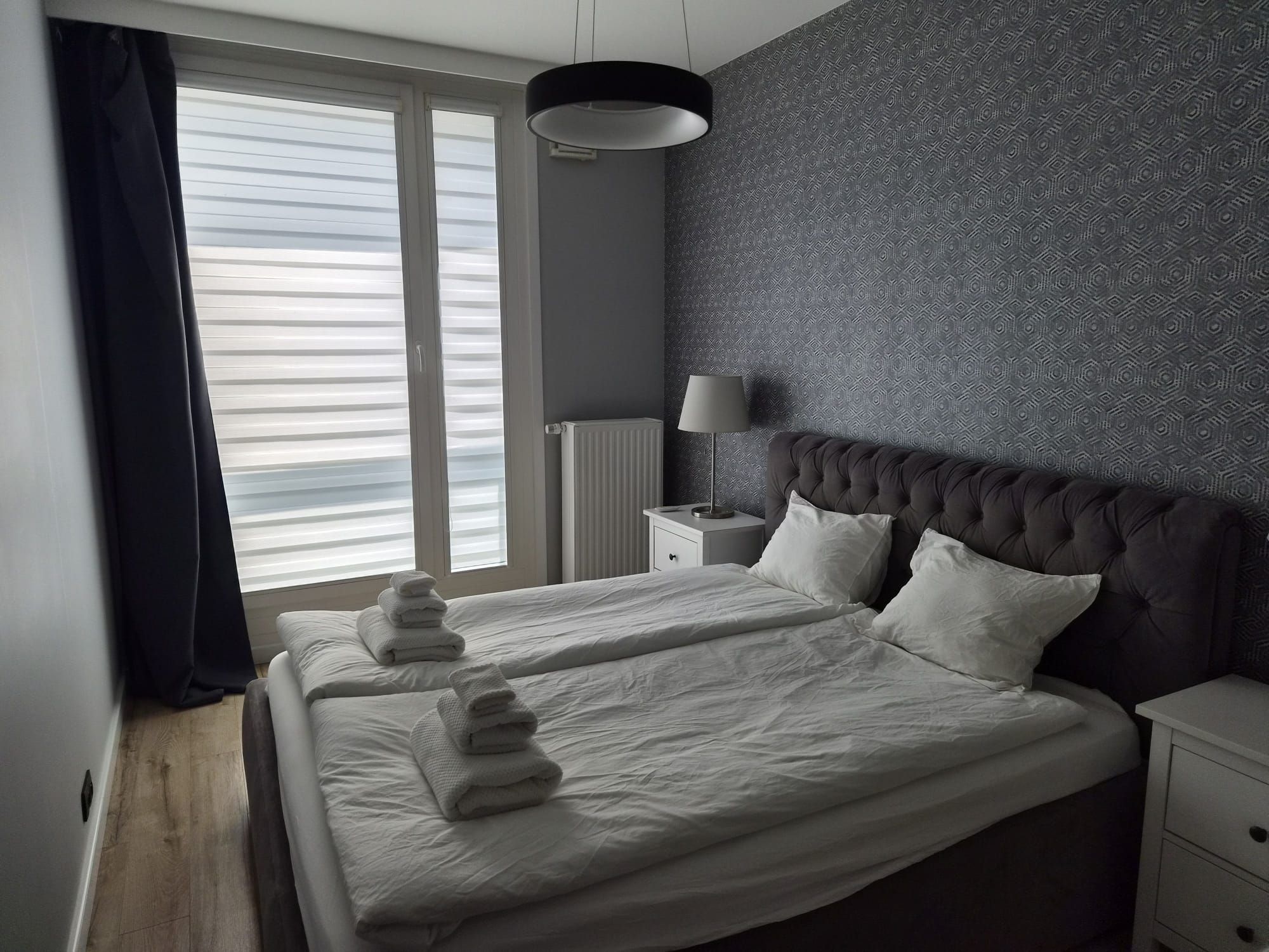 Una habitación de hotel con una cama grande, una mesita de noche, una lámpara y un radiador.