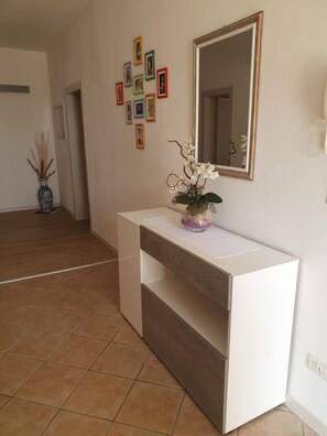 Ein modernes Interieur mit einer weißen Konsole, einem Spiegel und einer Vase mit Blumen.