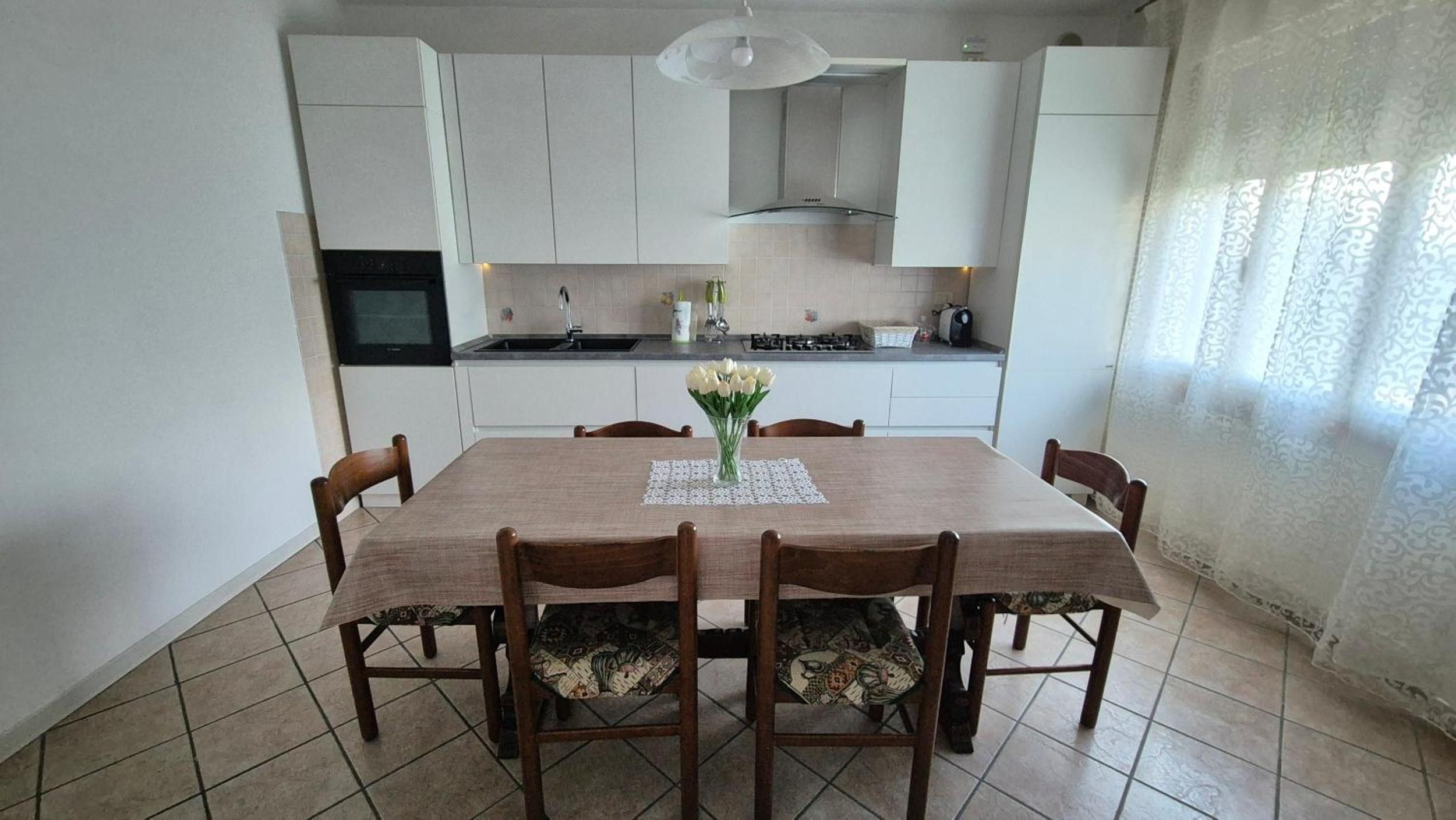 Een eethoek met een tafel, stoelen en een bloevas.