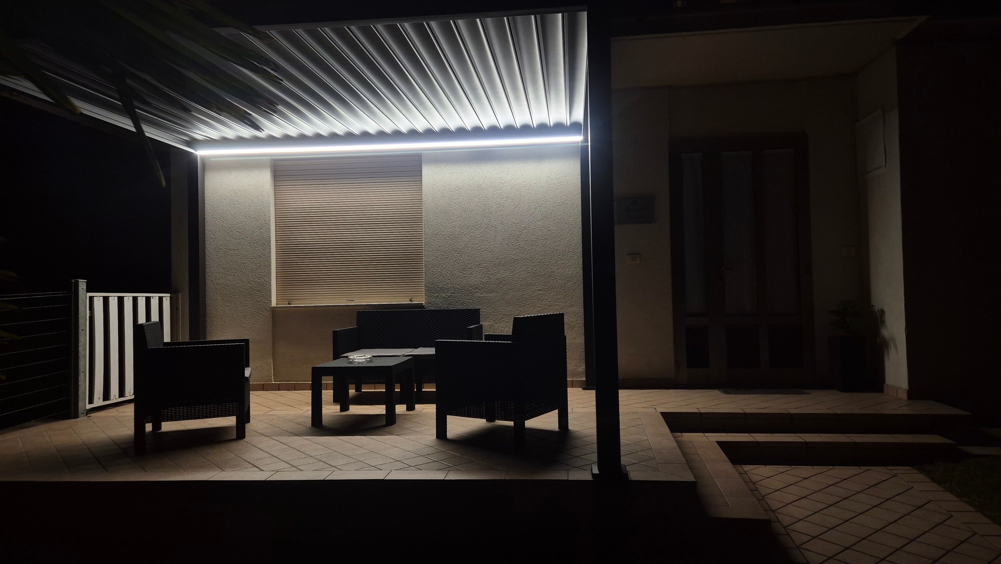 An outdoor patio area with a table and chairs, a covered seating area, and a wall with a window.