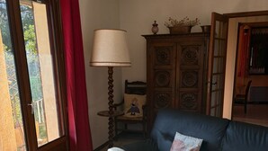 A living room with a sofa, a table, a lamp, and a cabinet. - Holiday Home 'Maison Tout Confort, Équipée' with Private Terrace, Wi-Fi and Air Conditioning (Saint-Gilles)