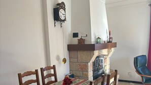 A dining area with a table set for four, a fireplace, and a clock on the wall. - Holiday Home 'Maison Tout Confort, Équipée' with Private Terrace, Wi-Fi and Air Conditioning (Saint-Gilles)