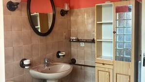 A bathroom with a pedestal sink, a mirror, a cabinet with glass doors, and a towel rack. - Holiday Home 'Maison Tout Confort, Équipée' with Private Terrace, Wi-Fi and Air Conditioning (Saint-Gilles)