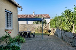 A patio area with a table and chairs, a barbecue grill, and a covered seating area.