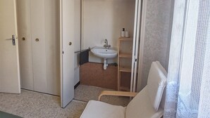 A room with a bed, a chair, a wardrobe, a sink, and a shelf. - Holiday Home 'Maison Tout Confort, Équipée' with Private Terrace, Wi-Fi and Air Conditioning (Saint-Gilles)