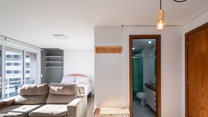 A modern apartment with a sofa, a bed, and a wooden shelf. - Studio in a Cond. With Pool, Setor Bueno - Txp1803 (Goiânia)