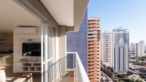 A balcony with a city view, a flat-screen TV, and a small kitchen area. - Studio in a Cond. With Pool, Setor Bueno - Txp1803 (Goiânia)