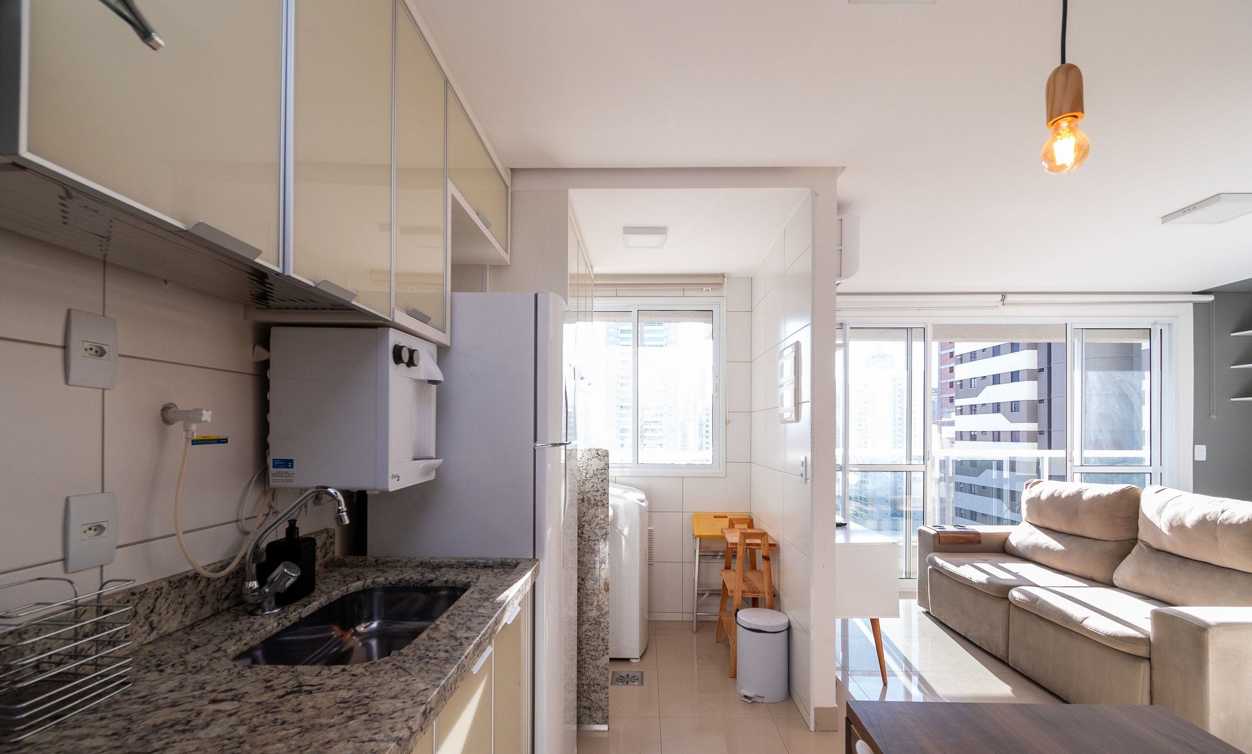 A modern kitchen with granite countertops, a built-in oven, and a window overlooking a cityscape.