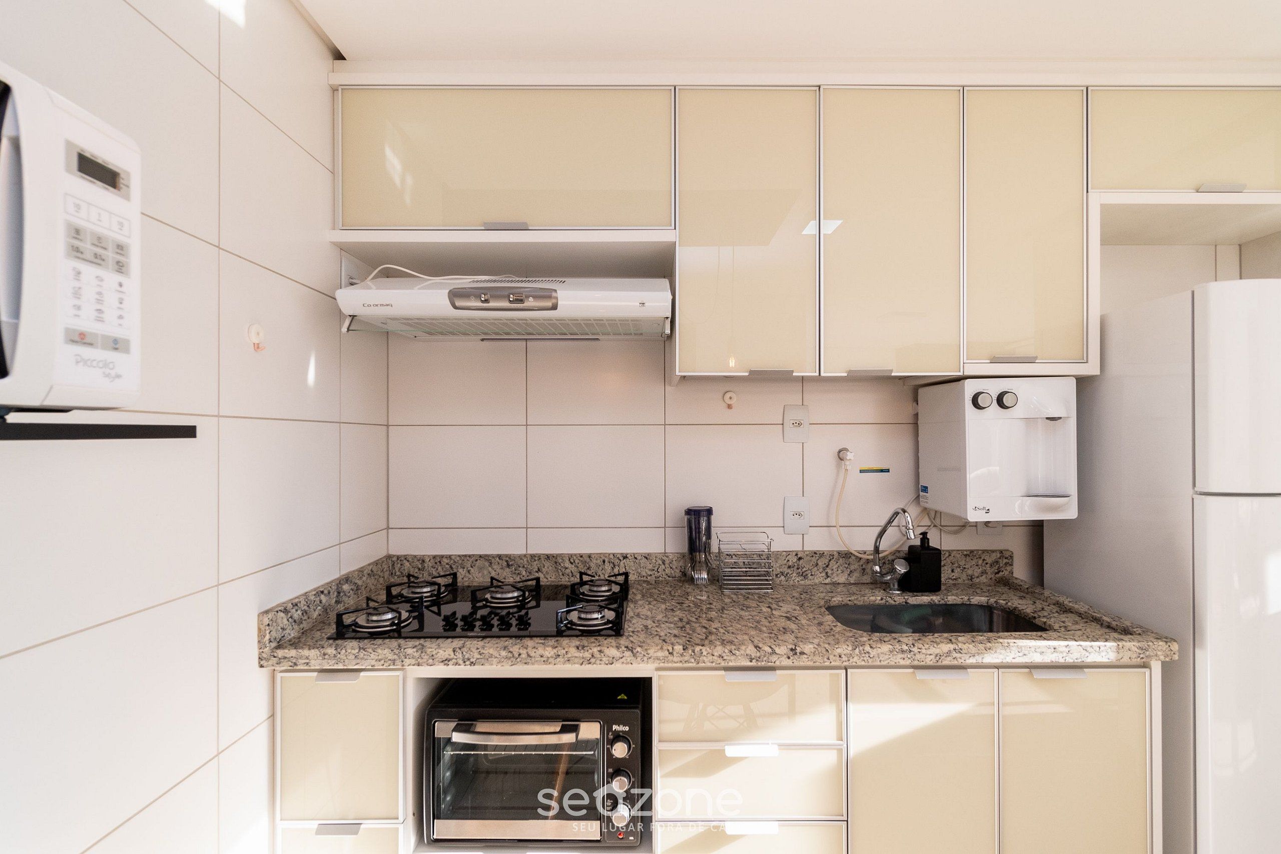 A compact kitchen with white cabinets, a granite countertop, a built-in oven, and a microwave.