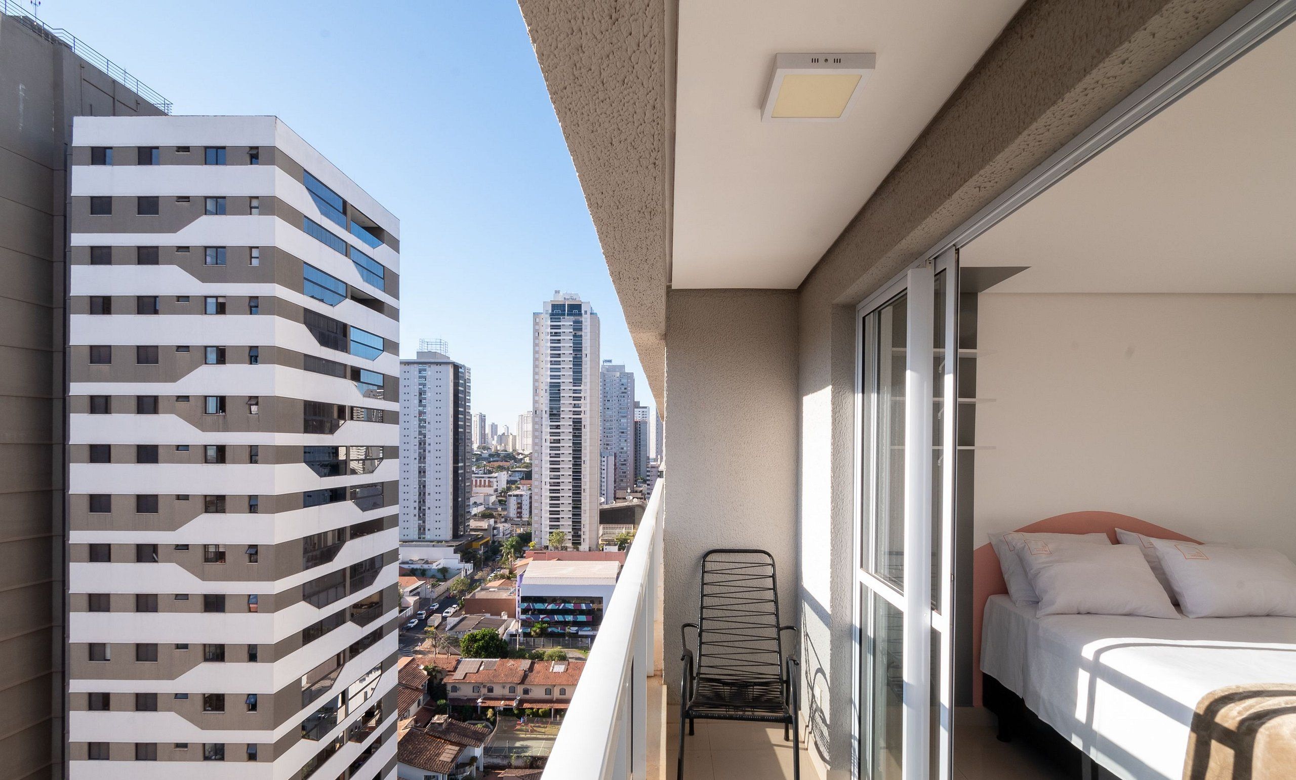 Een balkon met een bed, een stoel en uitzicht op de stadsgezicht.