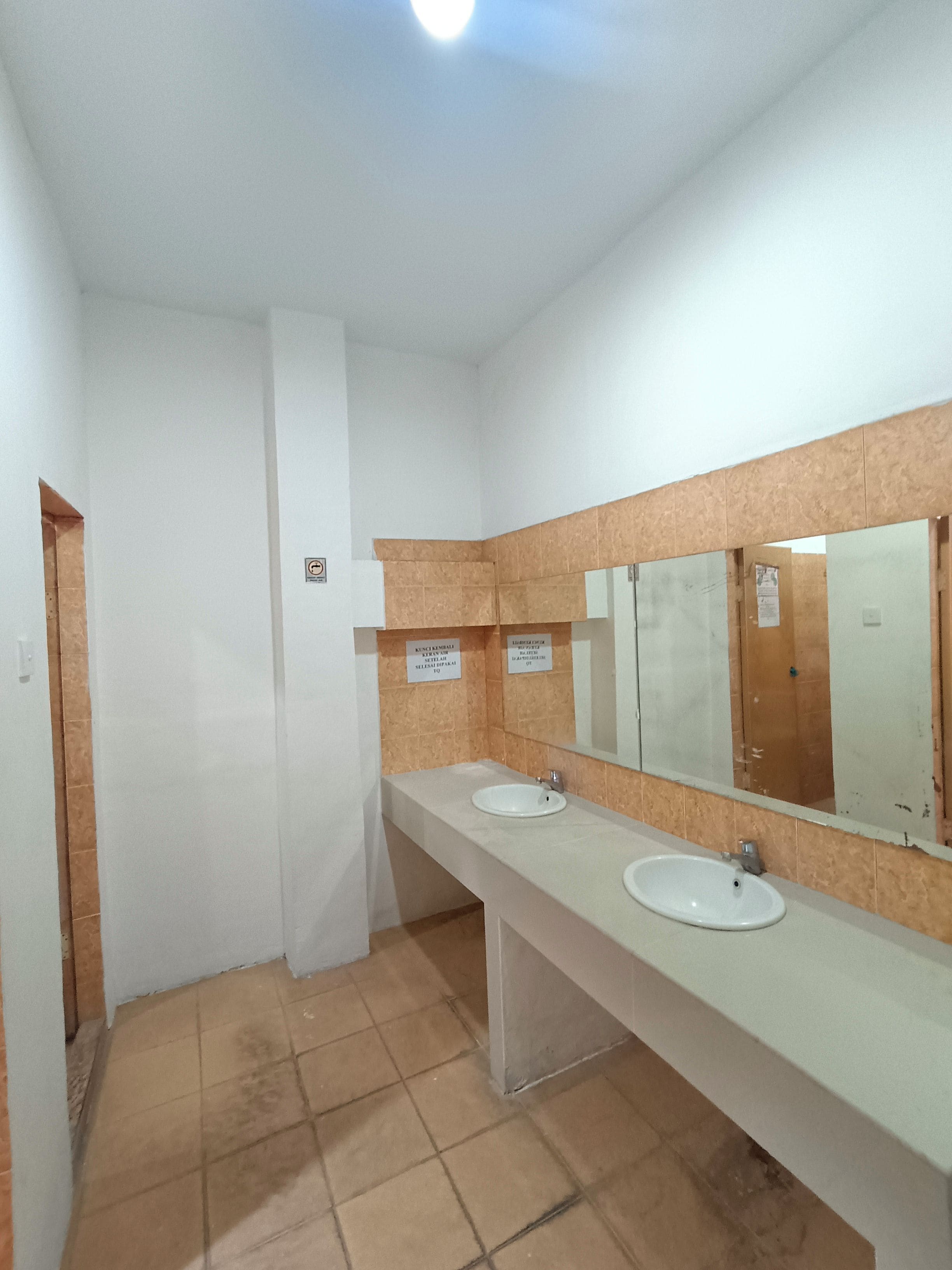 Un baño con dos lavamanos, un espejo y piso de baldosas.