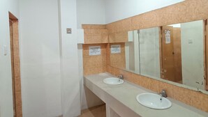 Un baño con dos lavamanos, un espejo y piso de baldosas.