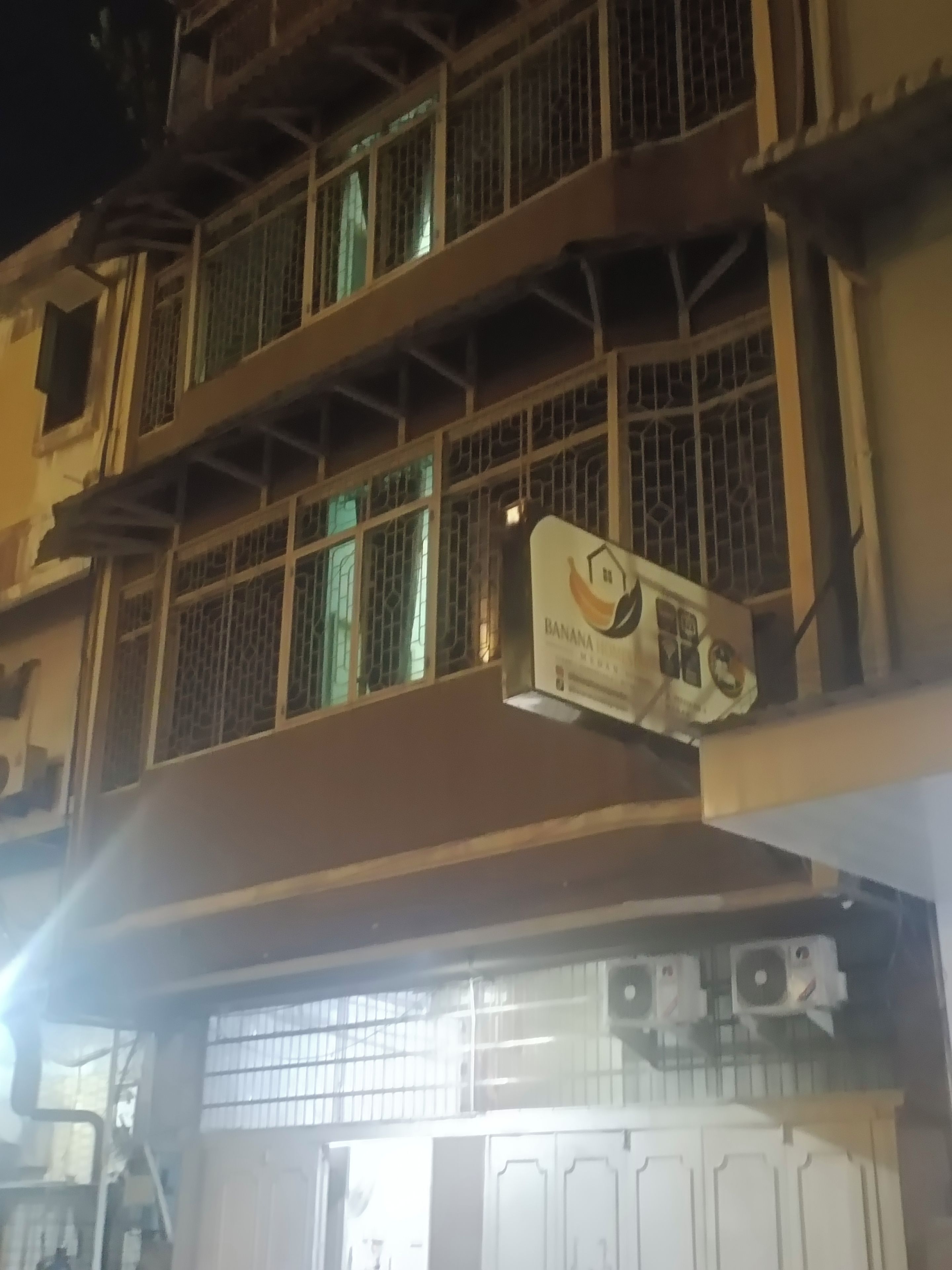 Un edificio de varios pisos con ventanas protegidas por rejas y un cartel que indica un restaurante llamado 'Banna'.