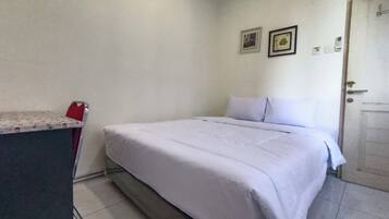 Una habitación sencilla con una cama, un escritorio y una puerta.