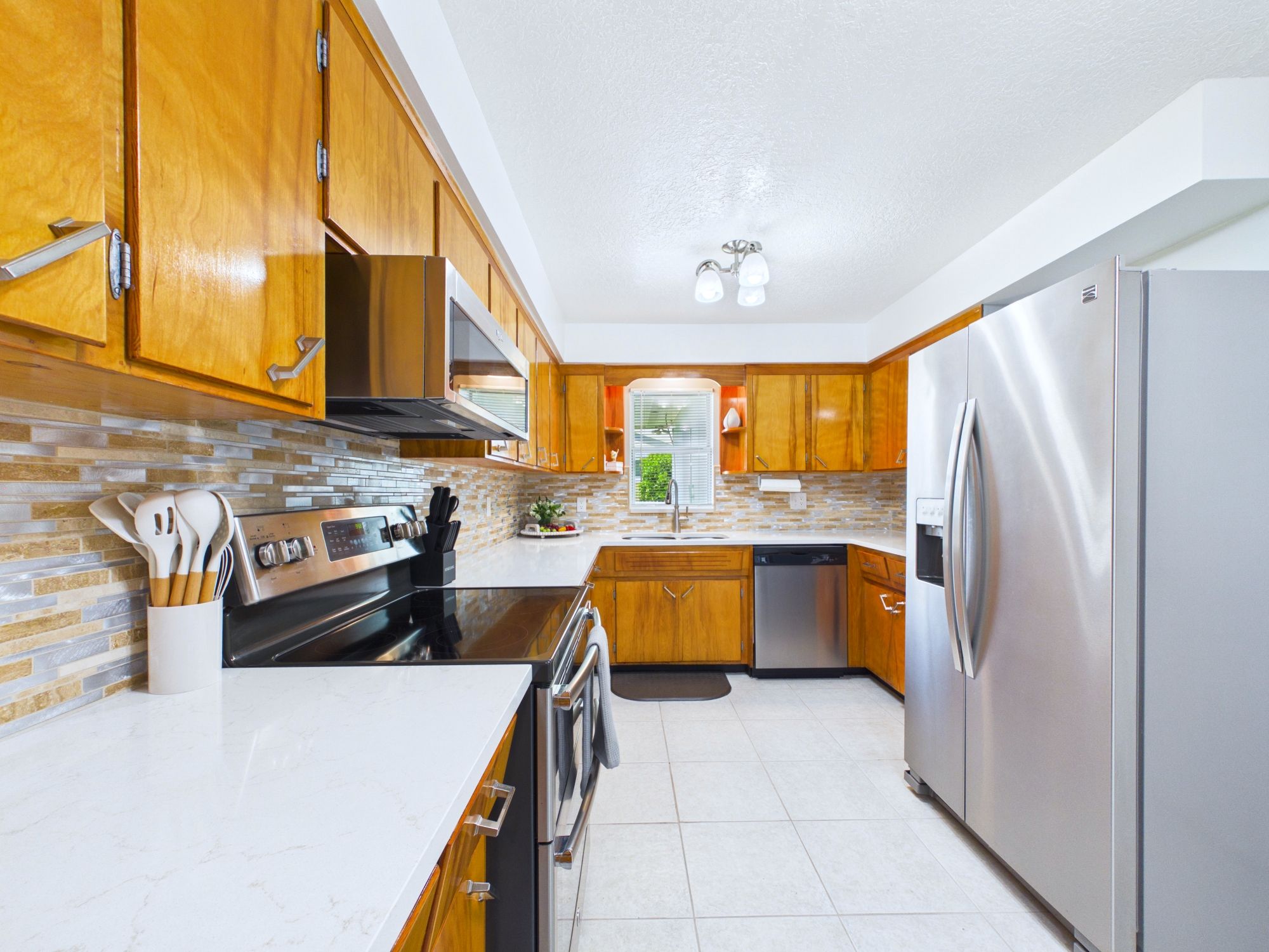 Una cocina moderna con armarios de madera, electrodomésticos de acero inoxidable y salpicadero de azulejos.