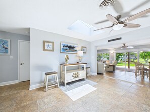 A spacious living area with a ceiling fan, a dining area with outdoor views, and a kitchen with a view of the outdoors. - Whether you're bringing your boat, planning a family vacation, or simply looking for a peaceful coastal retreat, this home delivers an unforgettable Space Coast experience. (Cocoa Beach)